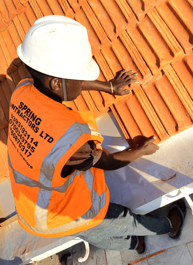 A side-by-side Roofing Materials Comparison showing iron sheets and clay tiles on a house in Kampala.