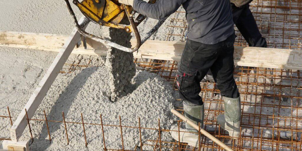 A professional engineer on a construction site in Kampala performing a slump test to verify the Concrete Grade C20 vs. C25 Standards for a new building.